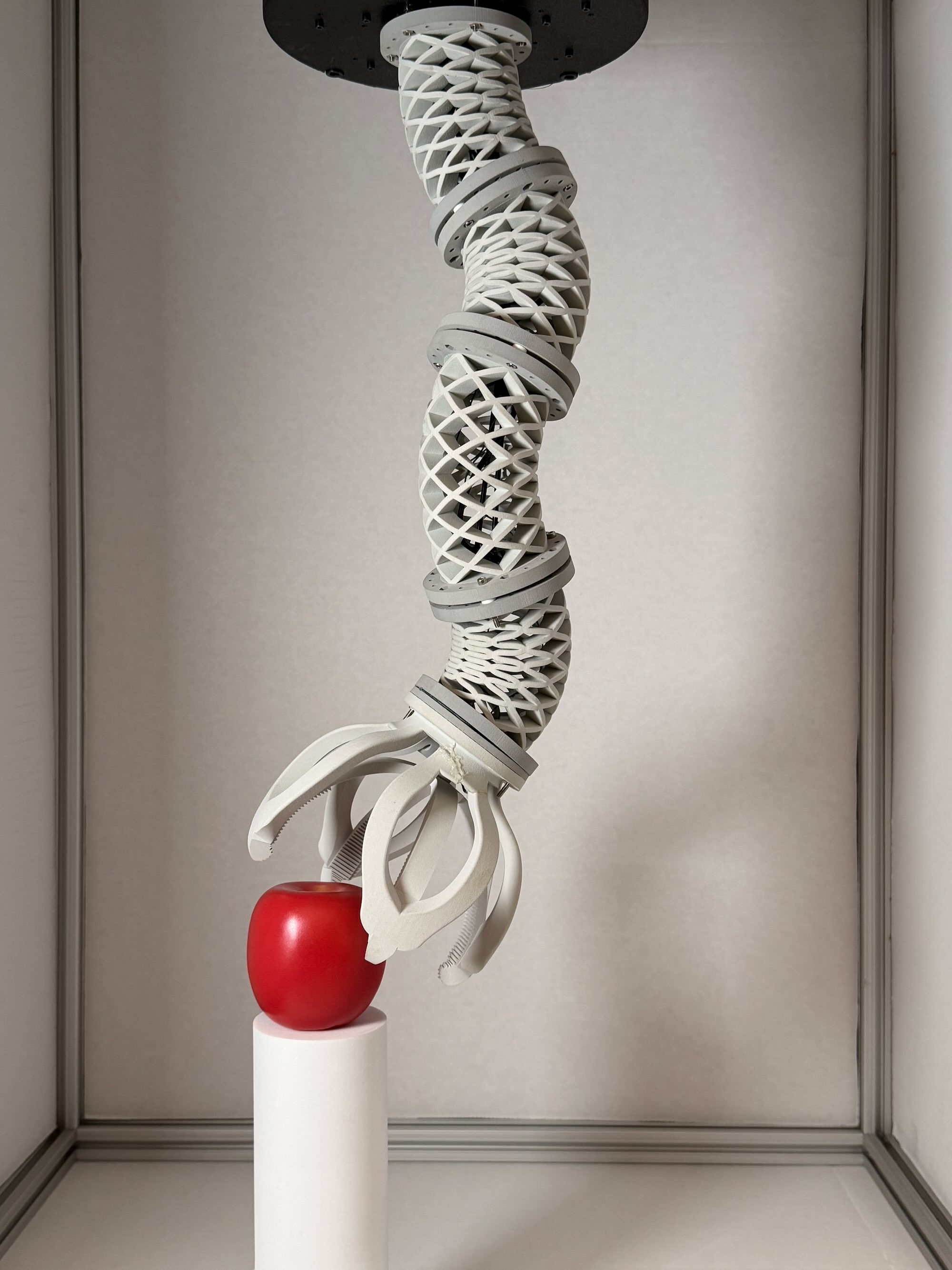 Printed helicoid robot segments bending toward an apple with a soft gripper